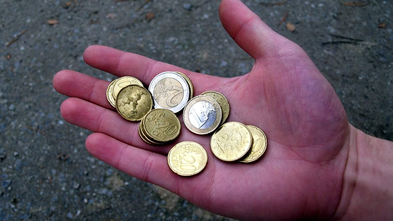 Main ouverte tenant quelques pièces de monnaie en euros